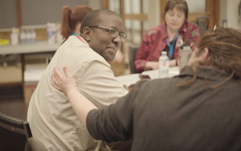 two committee members having a discussion while sitting at a round table with others