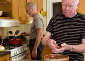 Mature married same-sex couple cooking in the kitchen