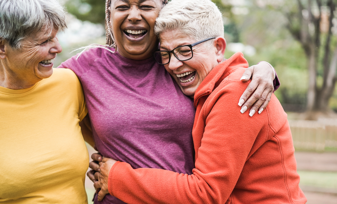 Three retired friends hugging after an outdoor workout.