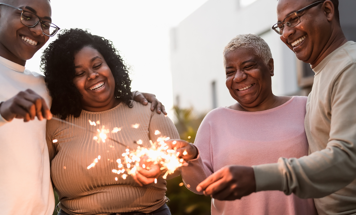 Quatre membres souriants d’une famille célèbrent la retraite de leurs parents avec un vin mousseux.