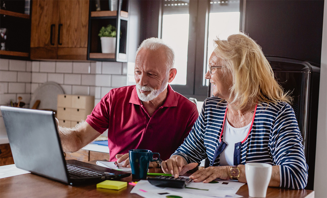 A couple using a laptop at their kitchen table to research donation options