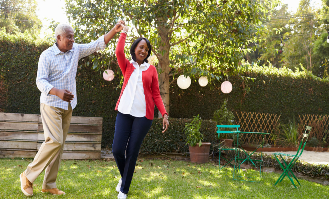 Retired couple dancing in their yard on a sunny day