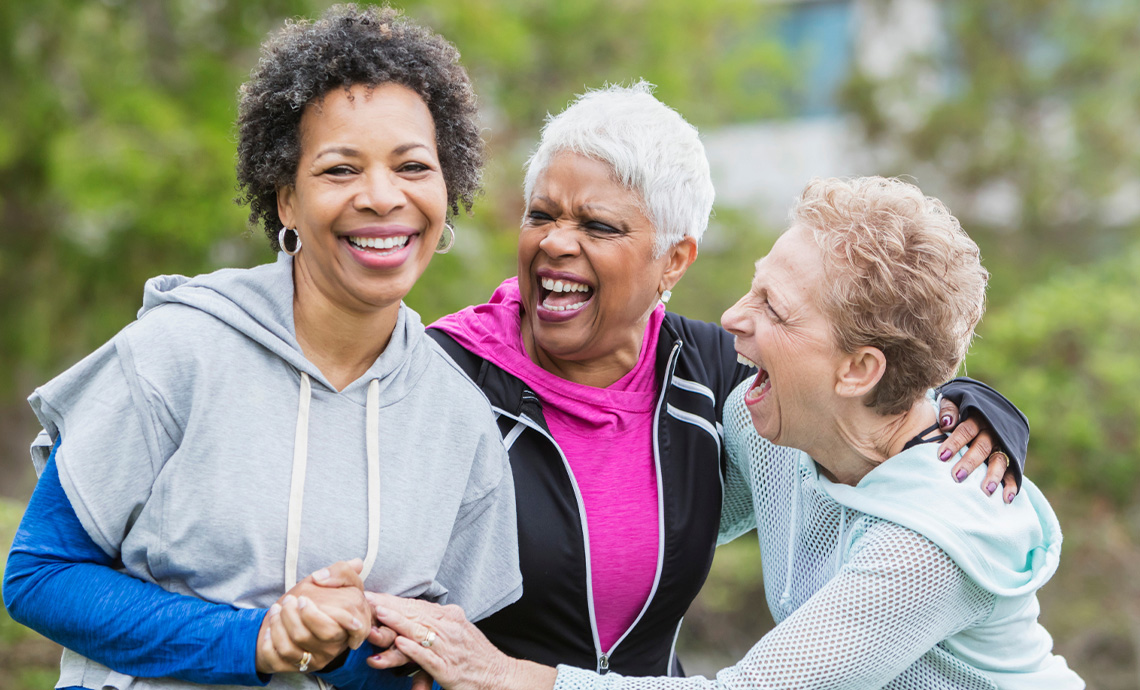 three older friends outside walking and laughing