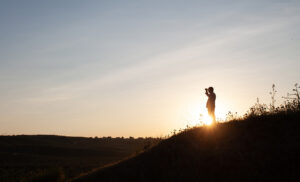 person on a hillside backlit by the sun