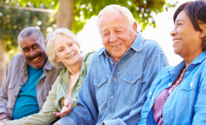 Four older friends sitting outside together laughing