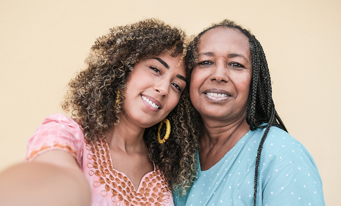 Friends posting for a selfie together against a beige wall