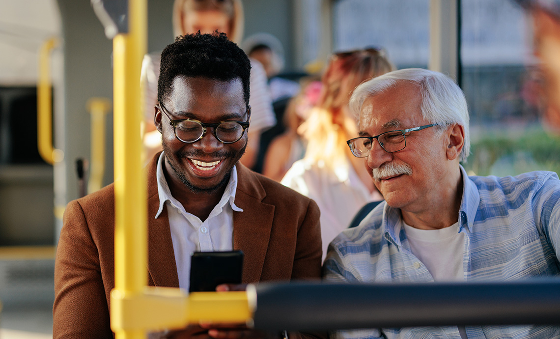 Older adult on a bus talking to a passenger beside them