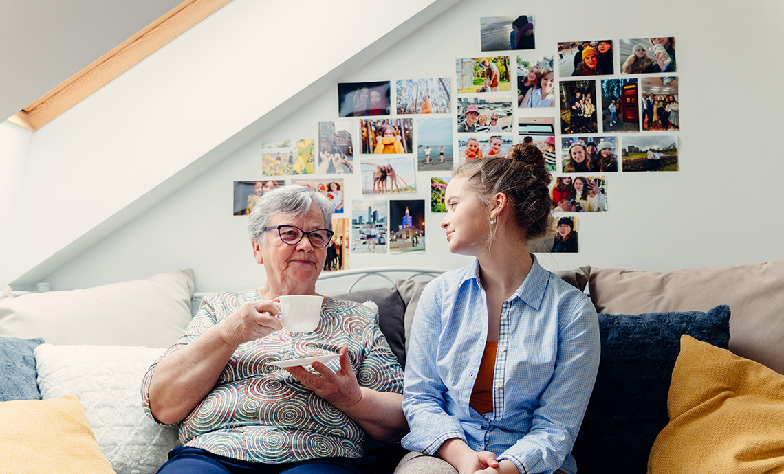 college student sitting on couch with older adult who has a cup of tea