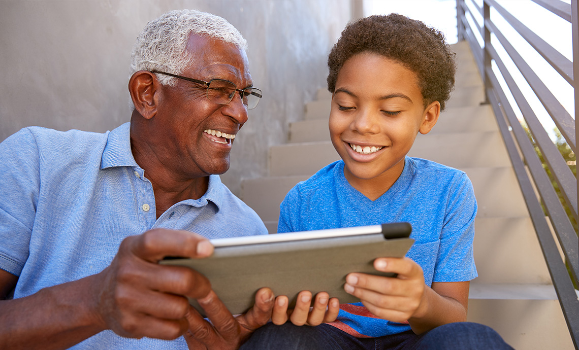 grandchild showing grandparent how to use a tablet computer