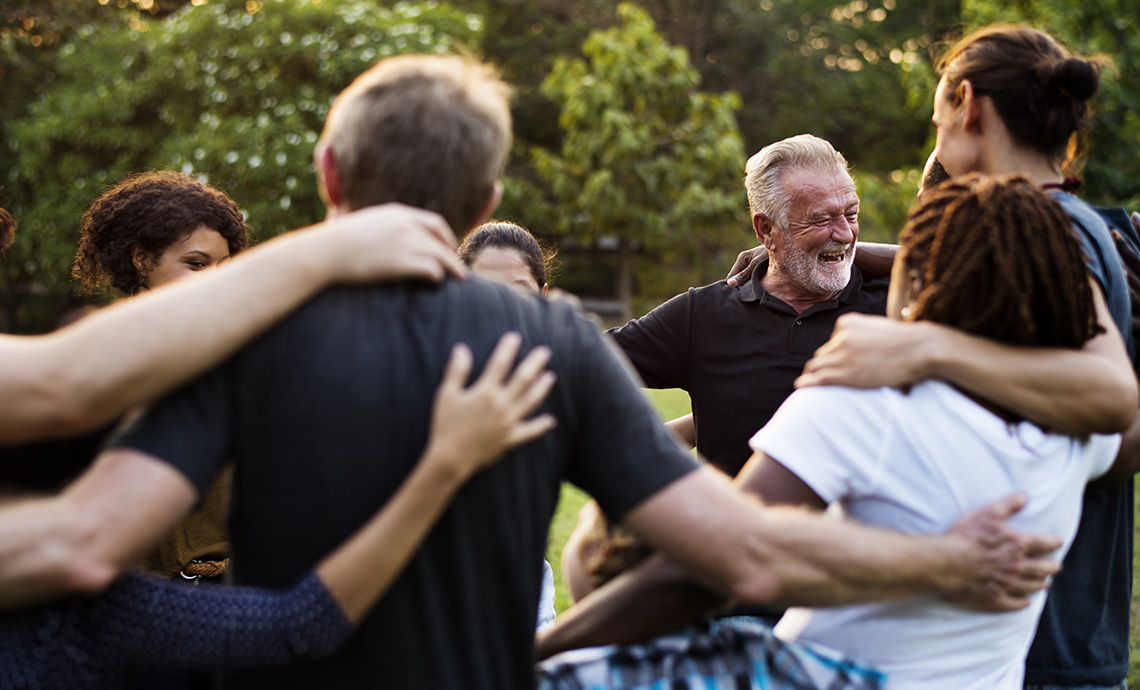 diverse group of community members with arms around eachother