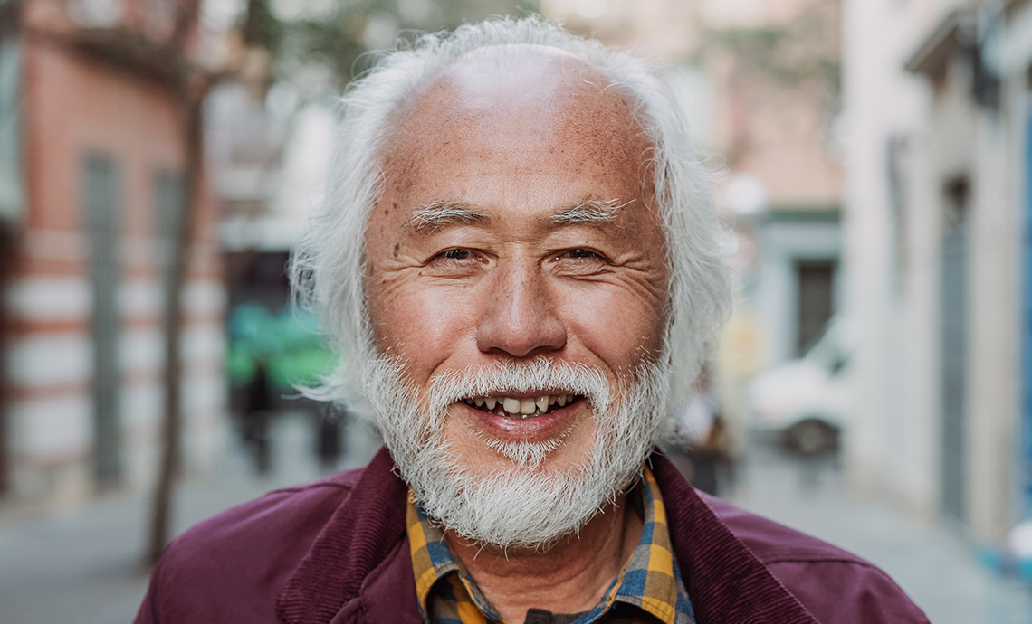 Close up of older adult outside in urban neighborhood smiling