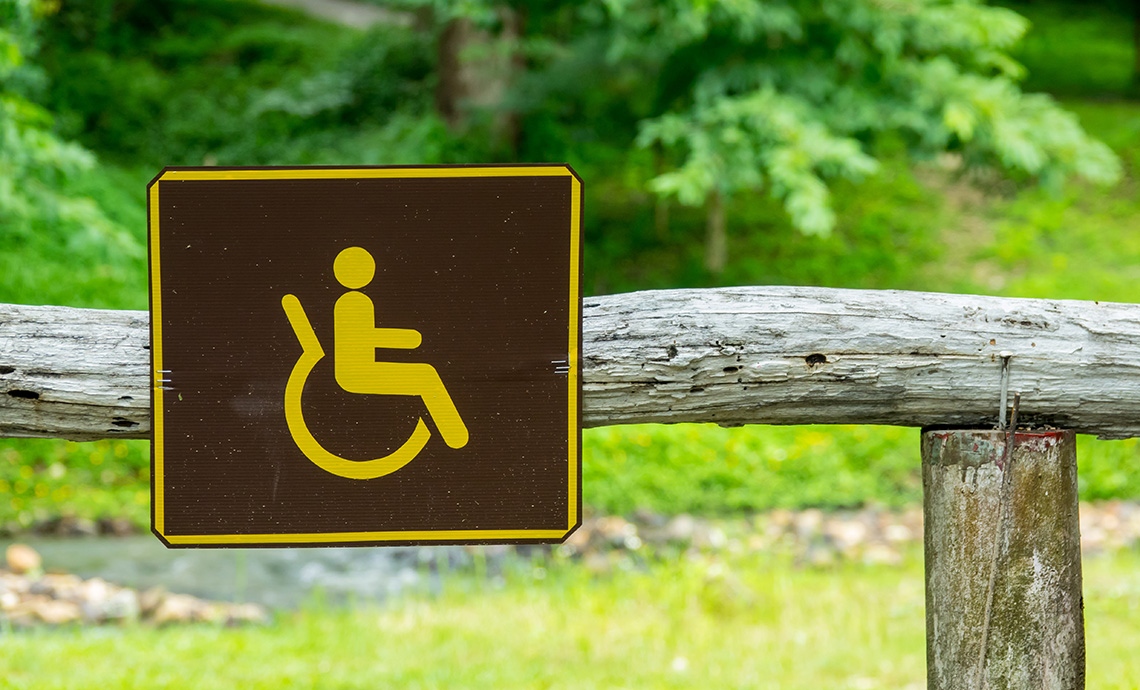 panneau d'accessibilité sur une clôture au départ d'un sentier forestier accessible