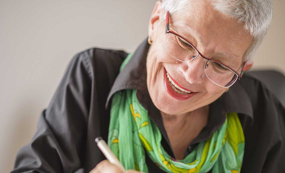 Older adult writing notes in a notebook