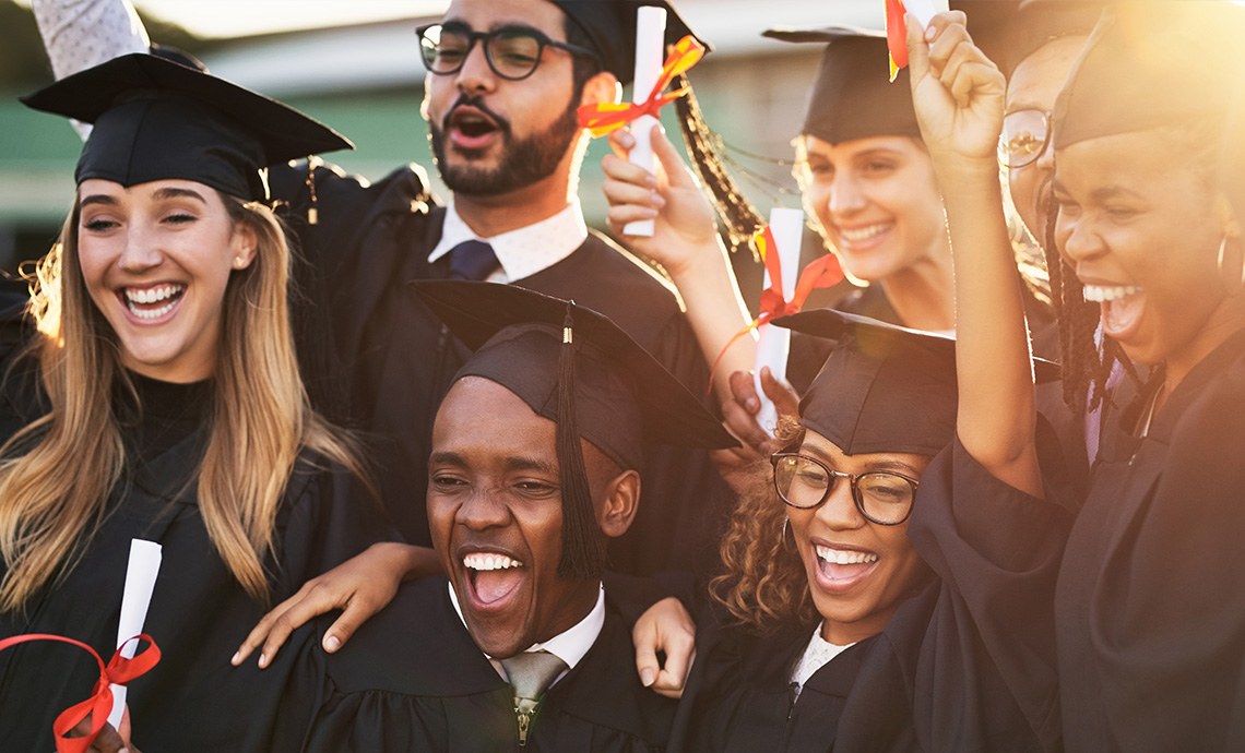 A group of graduates in caps and gowns looking happy