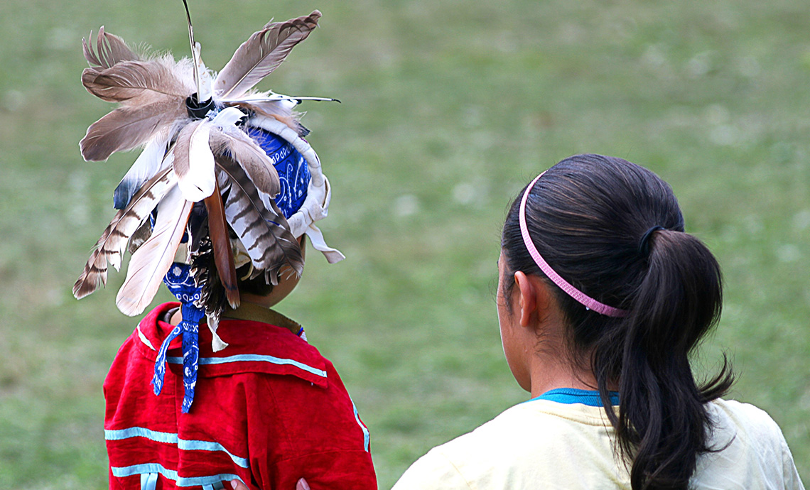 An Indigenous child dressed in regalia ready to take part in a ceremonial activity